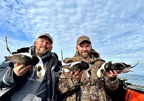  Two men holding up ducks caught on hunting trip