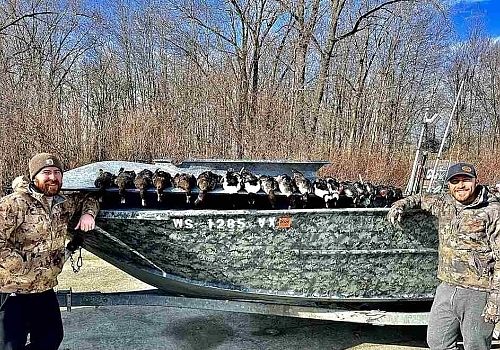 Two men show off ducks hunted in boat