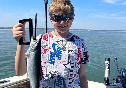 Young boy holds up fish caught on family trip