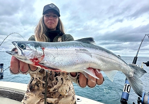 Woman holds up catch from fishing charter